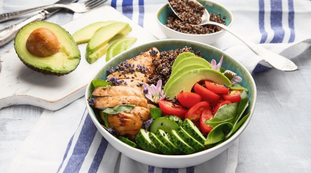 Delicious, colorful and healthy quinoa bowl with chicken, avocado, and cherry tomatoes.